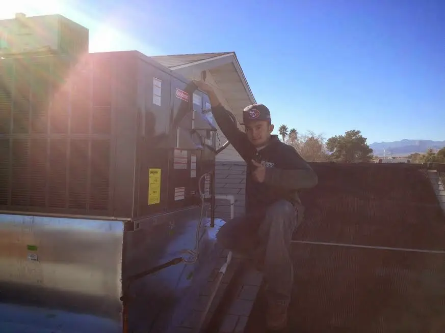 HVAC technician performing AC Tune-Up on a rooftop unit in Alpine